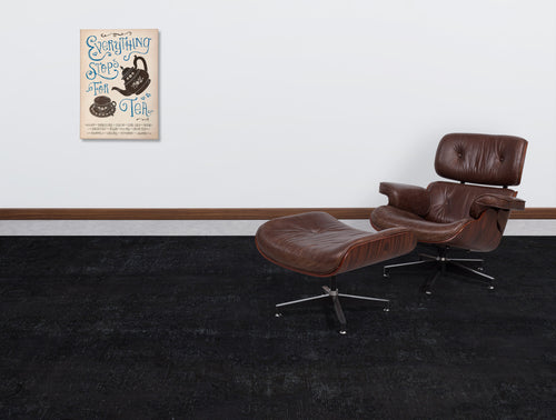 Load image 1 in gallery view. Solid black distressed-texture rug in a modern living room with a brown leather lounge chair and tea-themed wall art.