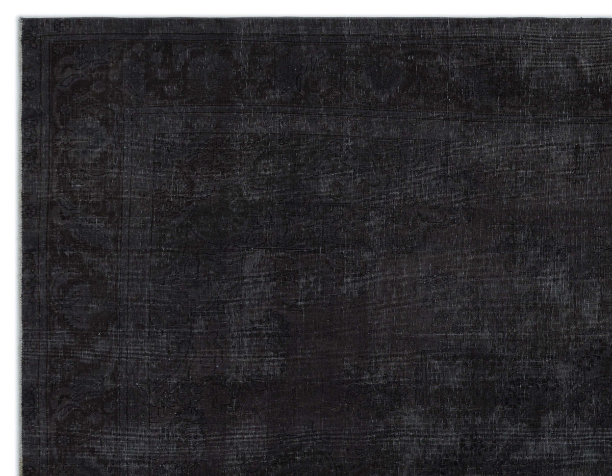 Monochromatic black rug with a subtle, distressed traditional floral medallion pattern and a wide border.