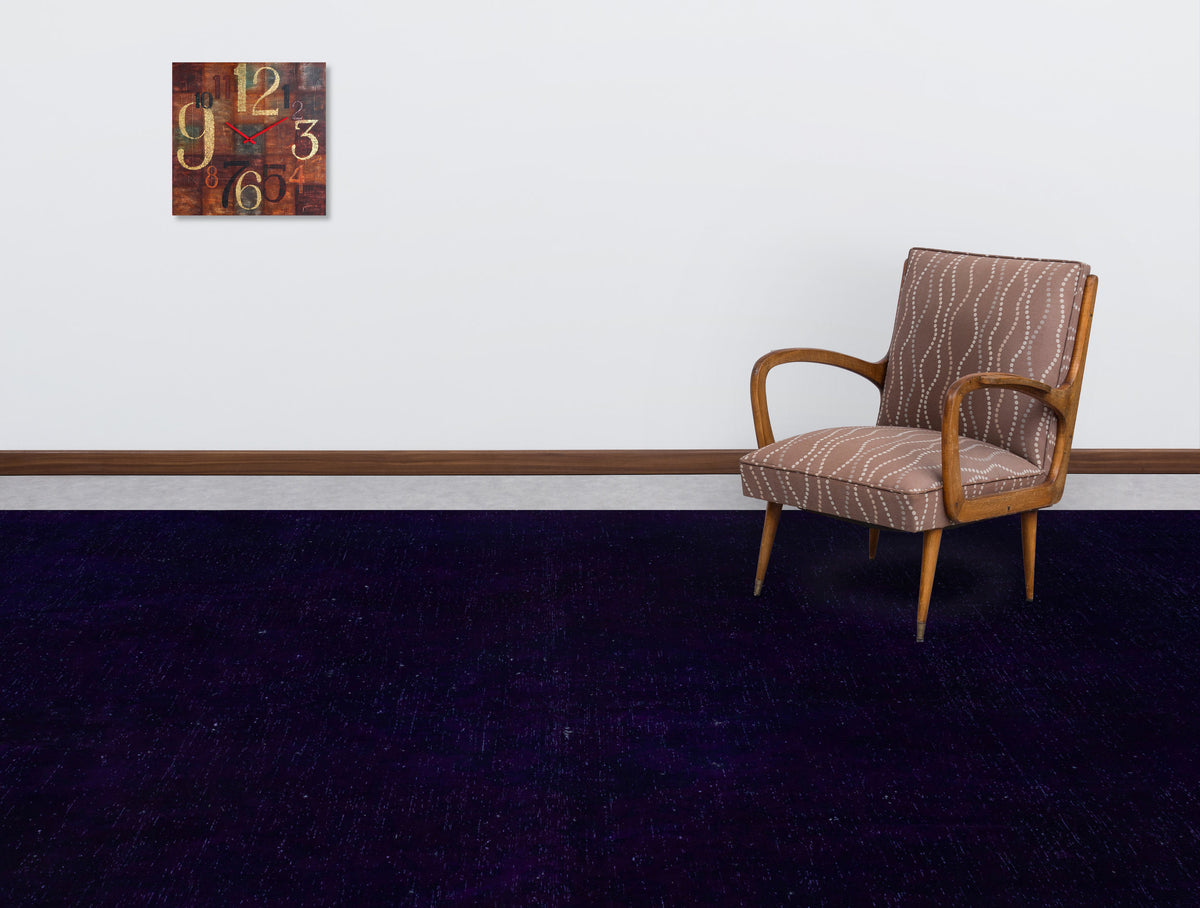 Solid deep purple rug in a room with a patterned armchair and a wall clock.