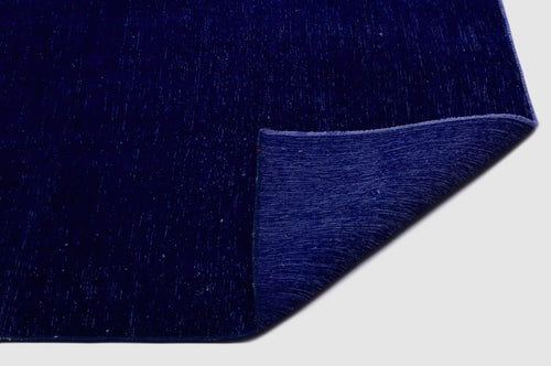 Load image 1 in gallery view. Solid deep blue rug with a distressed texture and a folded corner revealing the woven backing.