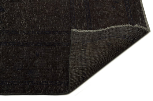 Load image 1 in gallery view. Dark brown distressed rug with a folded corner revealing the woven backing and fringe edge.