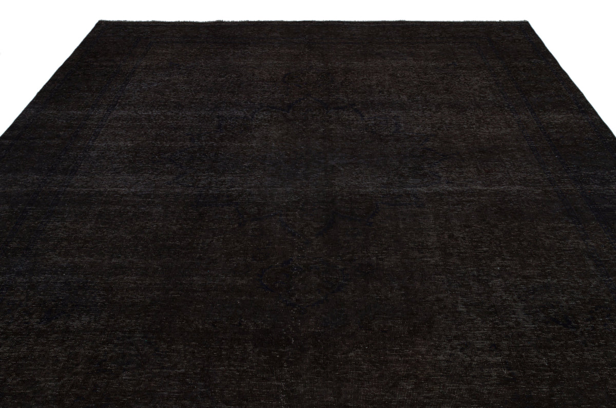 Solid black rug with a subtle, tonal distressed medallion pattern on a white background.