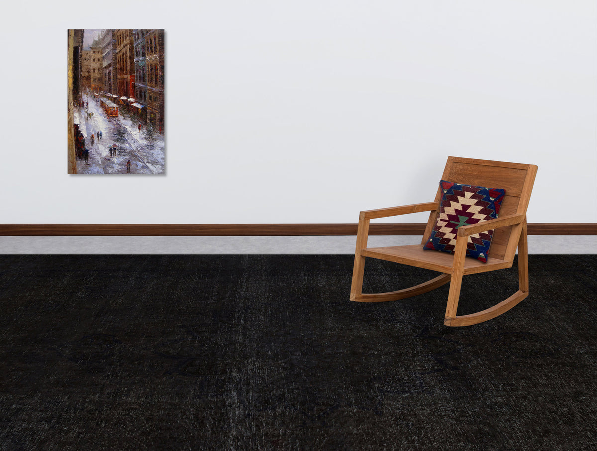 Solid black distressed-texture rug in a room with a wooden rocking chair and wall art.