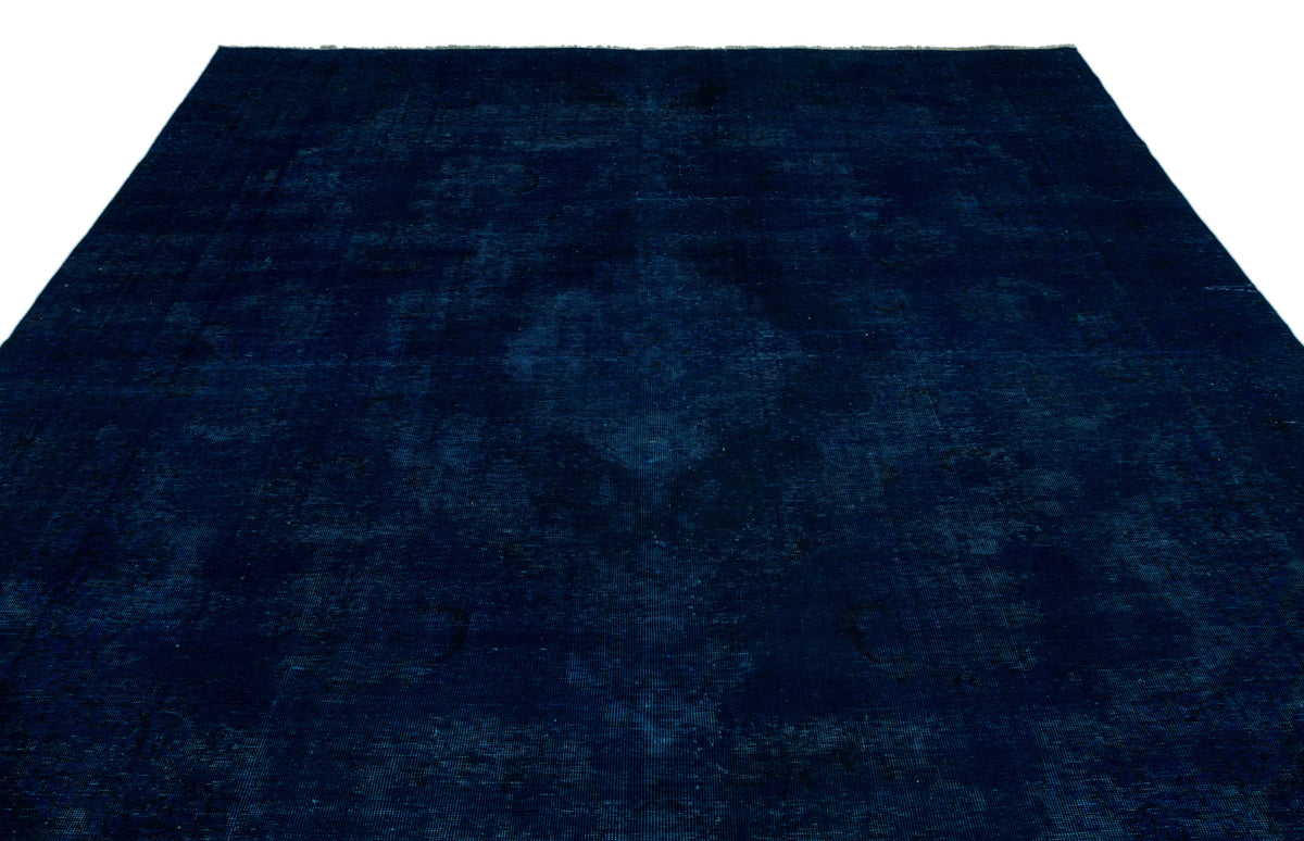 Solid navy blue rug with a subtle, distressed traditional medallion pattern on a white background.