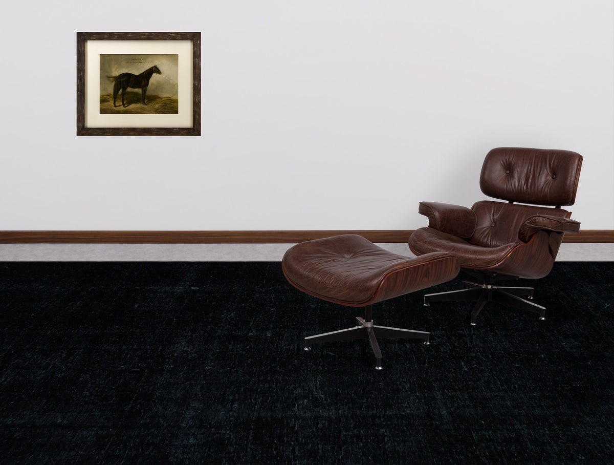 Solid black distressed-texture rug in a room with a brown leather lounge chair and a framed horse print.