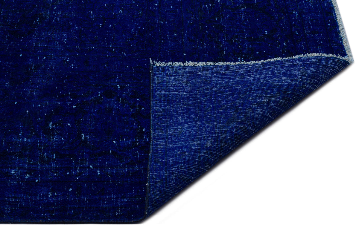 Deep blue distressed rug with a folded corner revealing the woven backing and white fringe.