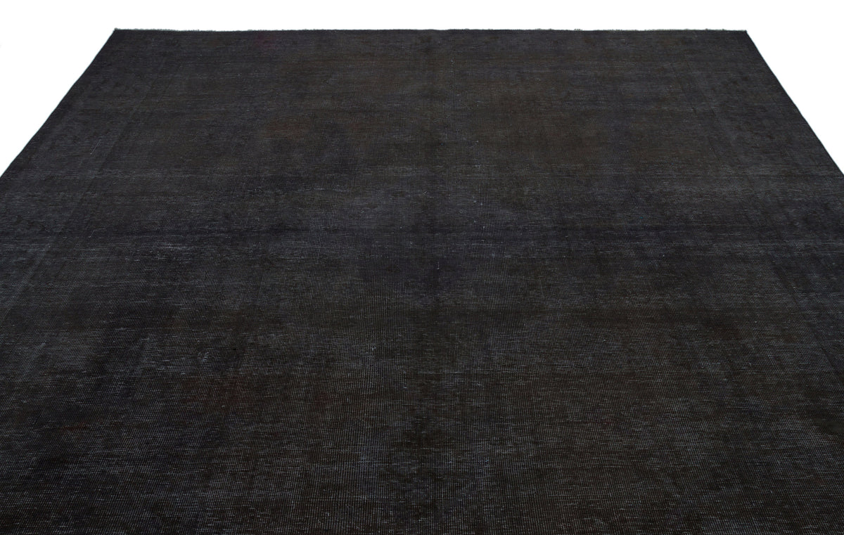 Solid black overdyed vintage rug with a subtle, distressed texture on a white background.