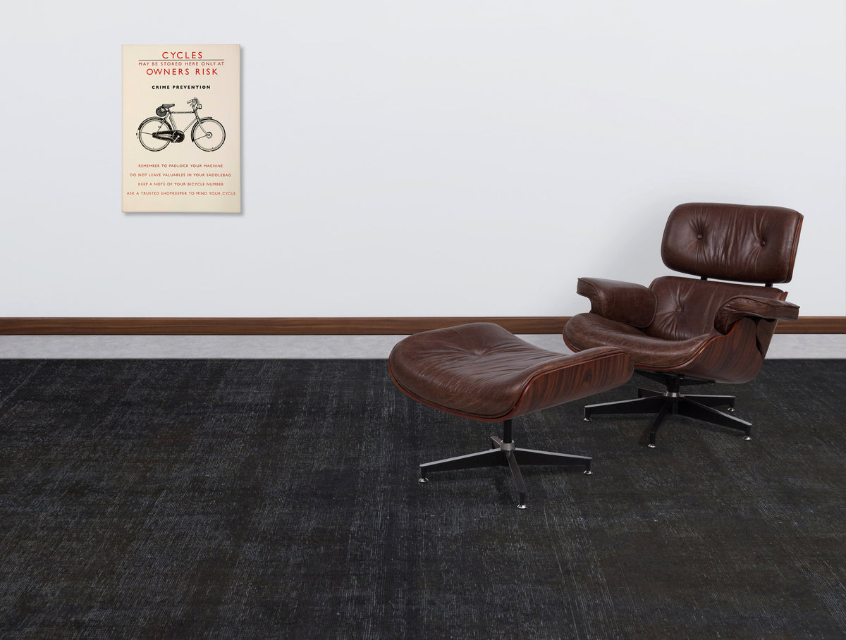 Solid black distressed-texture rug in a modern living room with a brown leather lounge chair and ottoman.