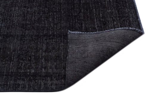 Load image 1 in gallery view. Charcoal black rug with a distressed texture and a folded corner revealing the grey woven backing.