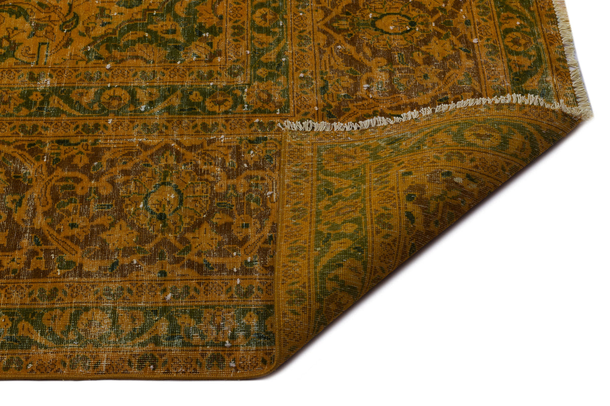 Distressed mustard yellow and green traditional rug with a floral medallion pattern and white fringe on a white background.
