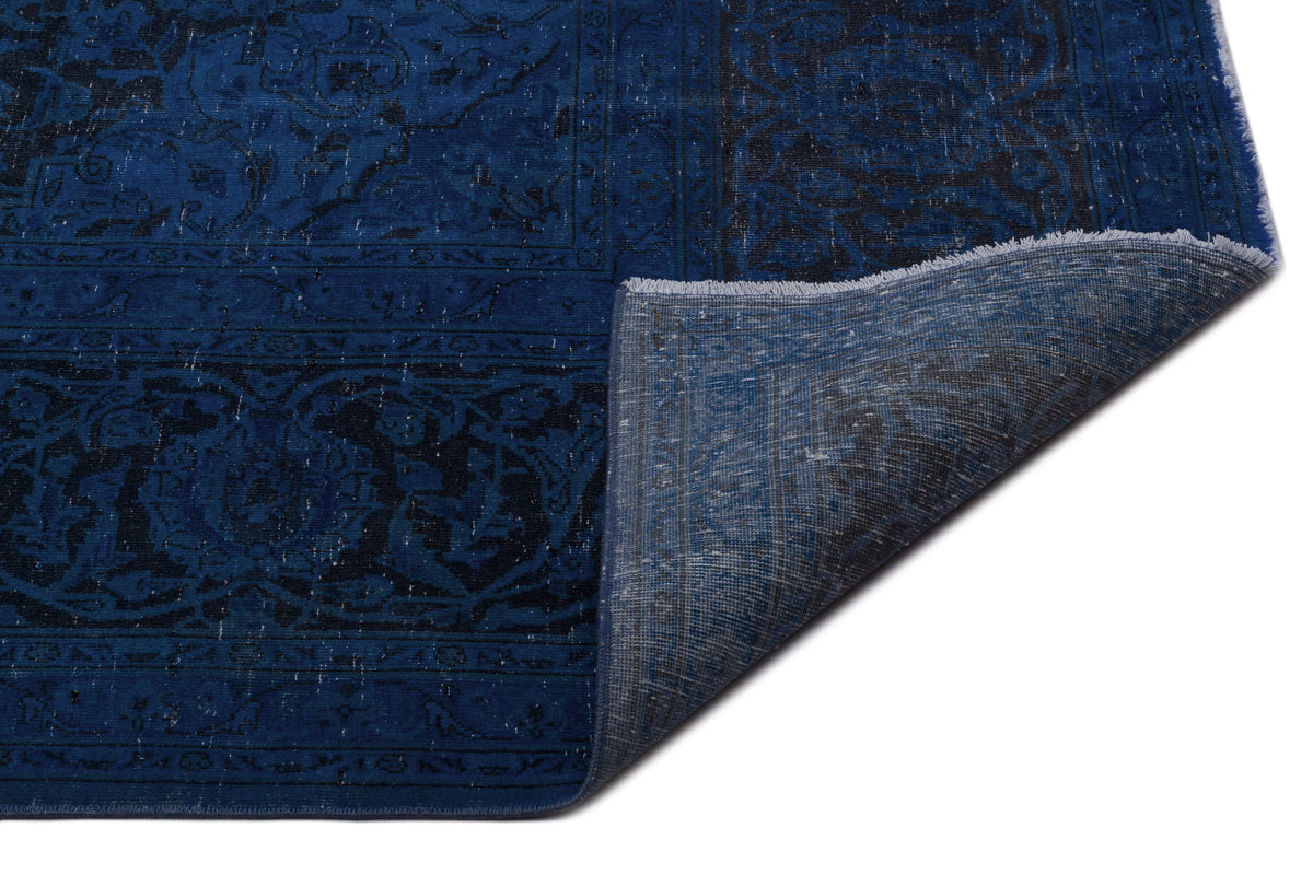 Deep blue and black traditional medallion rug with a distressed finish and a corner folded over to show the backing.