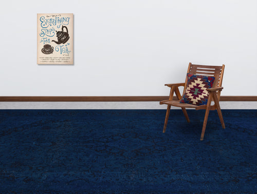 Load image 1 in gallery view. Solid navy blue rug with a subtle tonal floral pattern, styled in a room with a wooden chair and wall art.