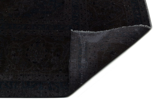 Load image 1 in gallery view. Black and charcoal traditional rug with a subtle medallion pattern, shown with a folded corner on a white background.