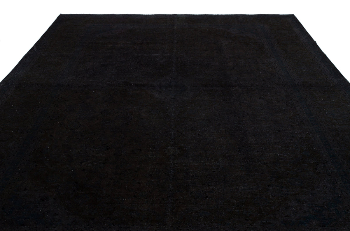 Solid black rug with a subtle, tonal distressed medallion pattern on a white background.