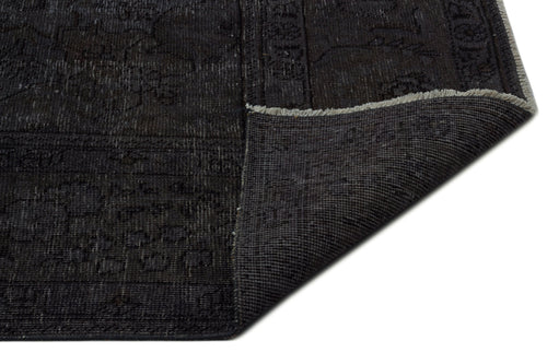 Load image 1 in gallery view. Charcoal black distressed rug with a faint traditional pattern and a folded corner showing the woven backing.