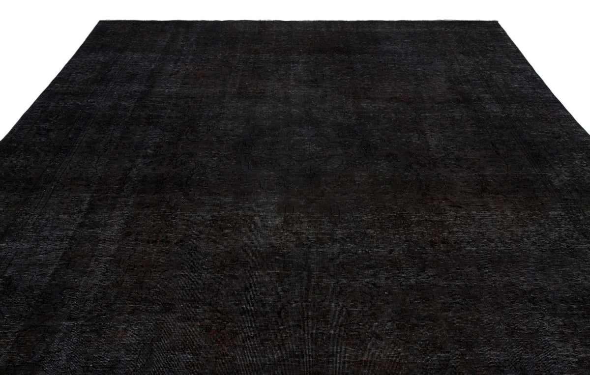 Solid black rug with a subtle, distressed traditional medallion pattern on a white background.