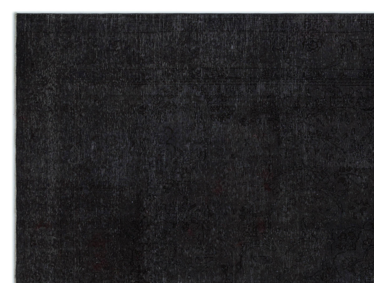 Solid black rug with a subtle, tone-on-tone distressed traditional floral pattern.