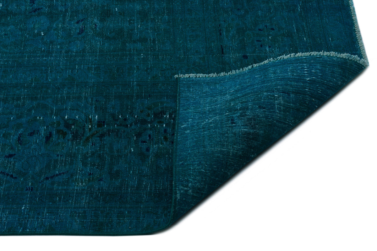 Deep teal distressed rug with a folded corner revealing the woven texture on a white background.