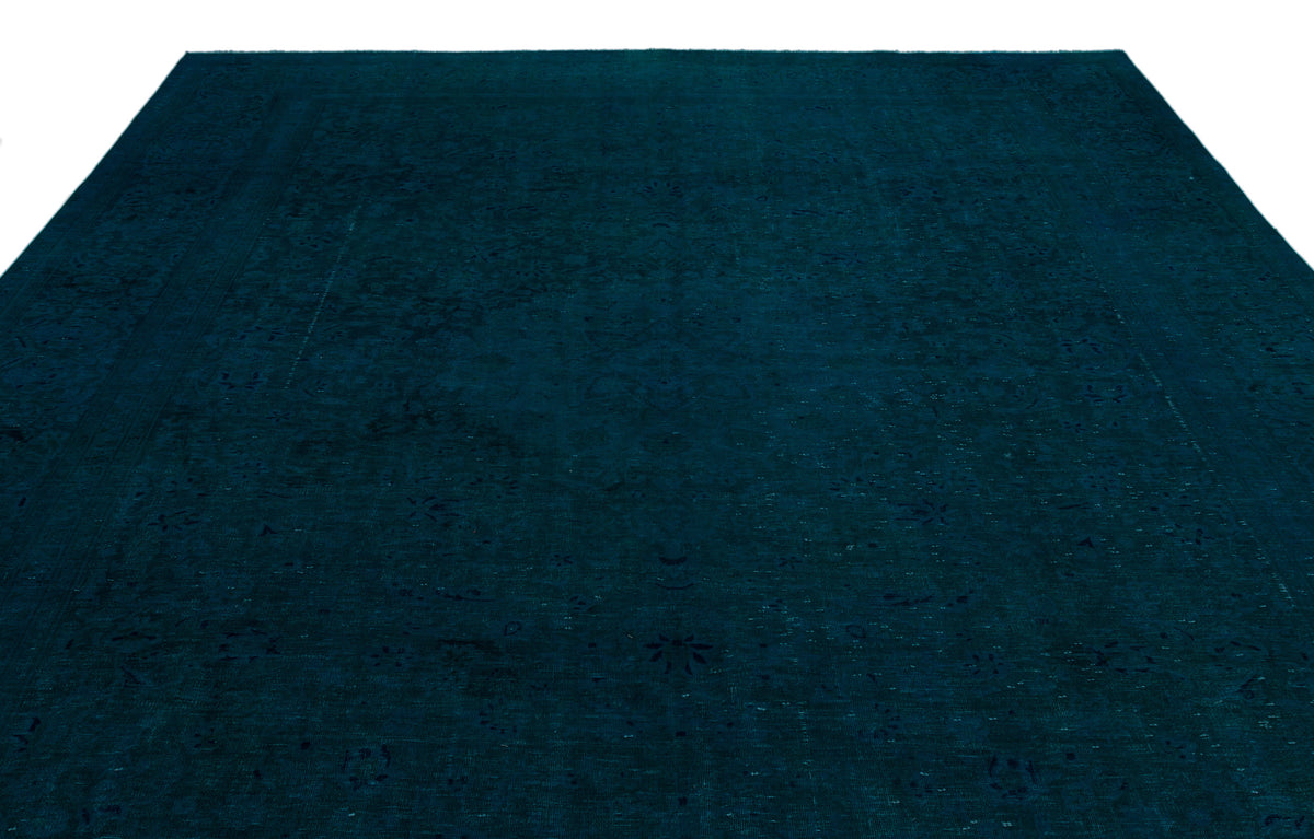 Deep teal monochromatic rug with a subtle, distressed traditional floral pattern on a white background.