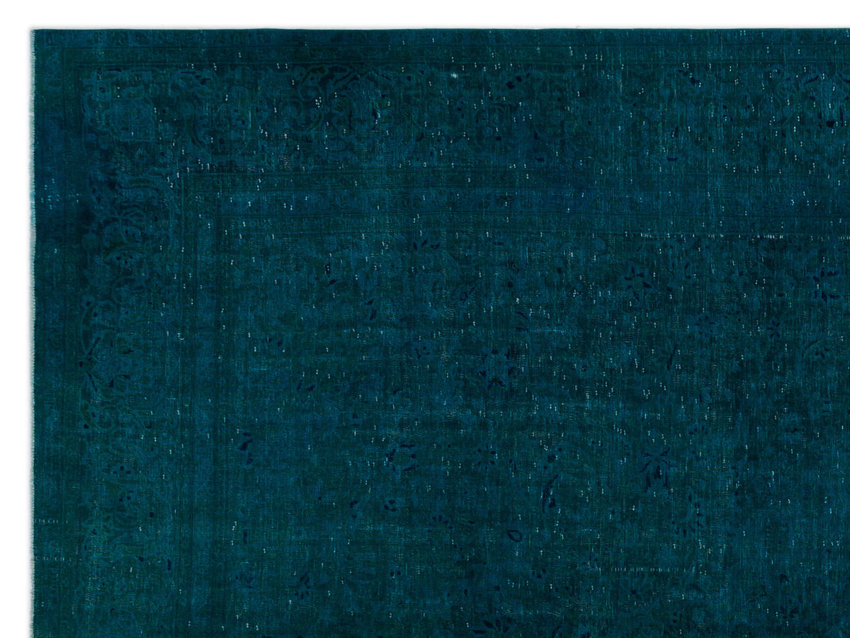Deep teal vintage-style rug with a subtle, distressed floral medallion pattern and a decorative border.