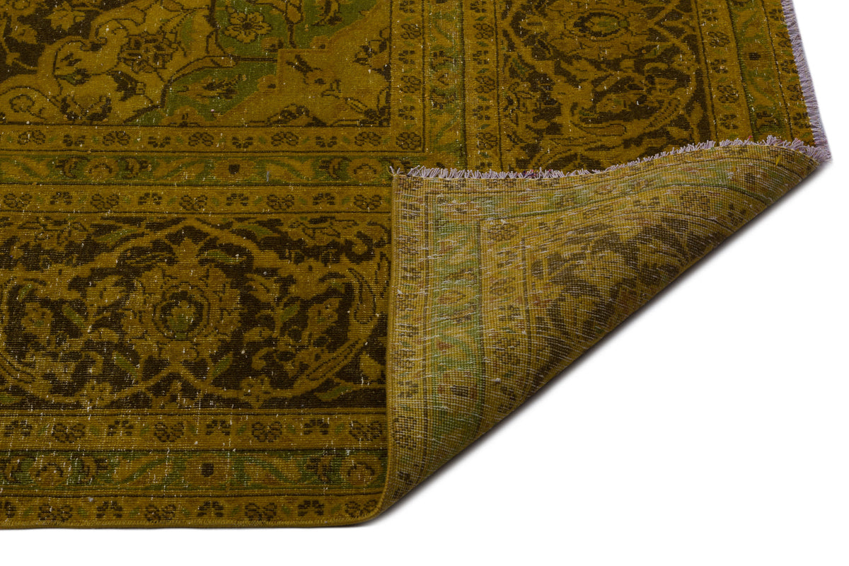 Olive and dark green vintage-style rug with a traditional floral medallion pattern and a folded corner.