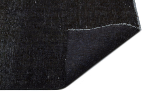 Load image 1 in gallery view. Solid black distressed rug with a folded corner revealing the woven backing and fringe edge.