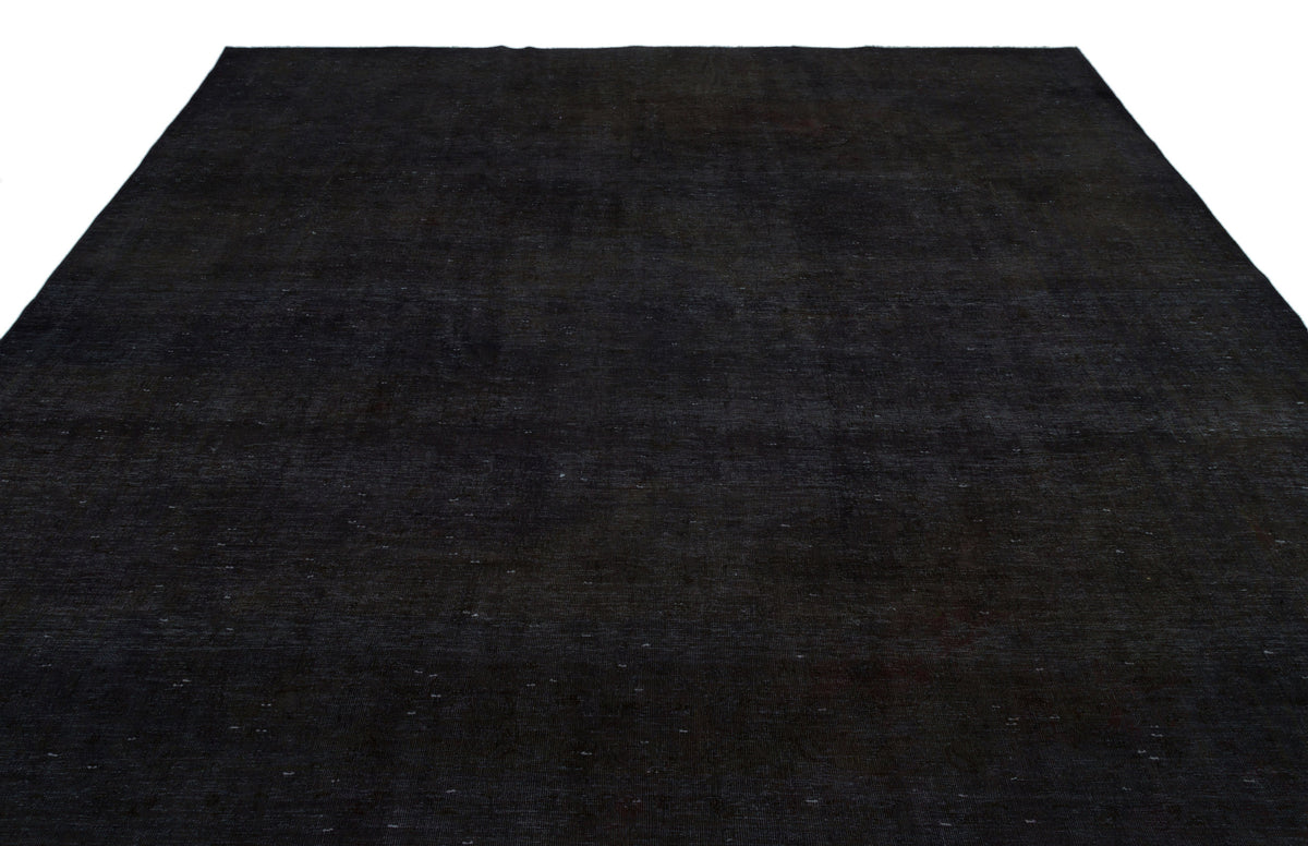 Solid black rug with a subtle, distressed texture and faint, scattered white flecks on a white background.