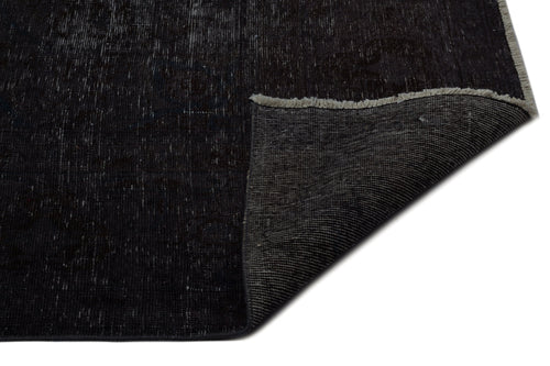 Load image 1 in gallery view. Distressed black and charcoal vintage-style rug with a folded corner revealing a woven backing and fringe edge.
