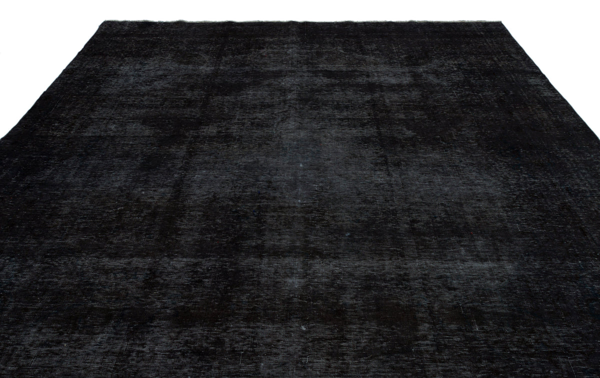 Solid black rug with a distressed, low-pile texture and subtle tonal variations.