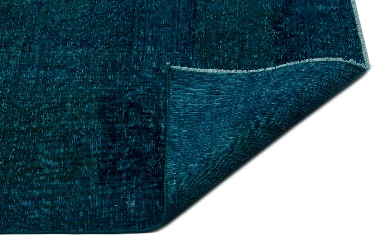 Deep teal distressed rug with a folded corner revealing the woven backing, isolated on a white background.