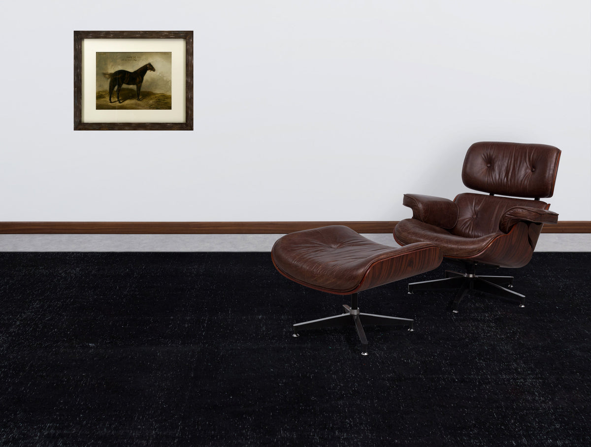 Solid black distressed-texture rug in a room with a brown leather lounge chair and a framed horse print.