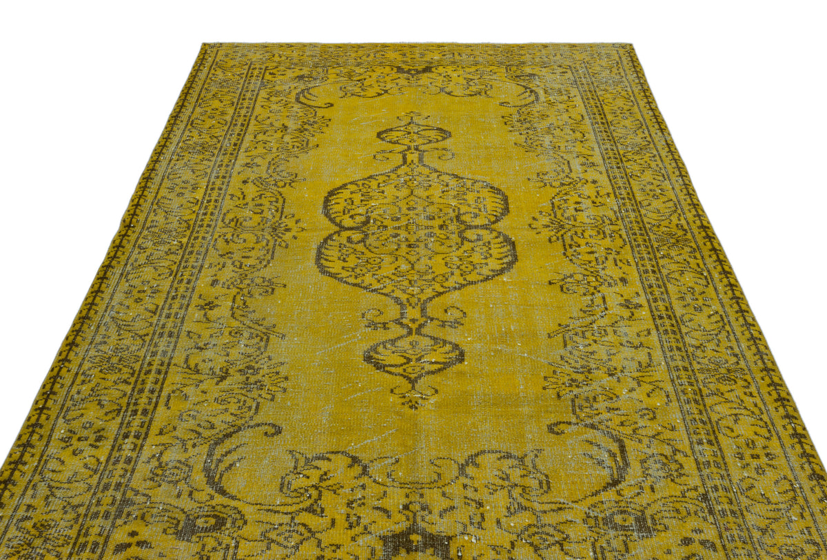 Distressed mustard yellow rug with a dark brown central medallion and ornate floral border on a white background.