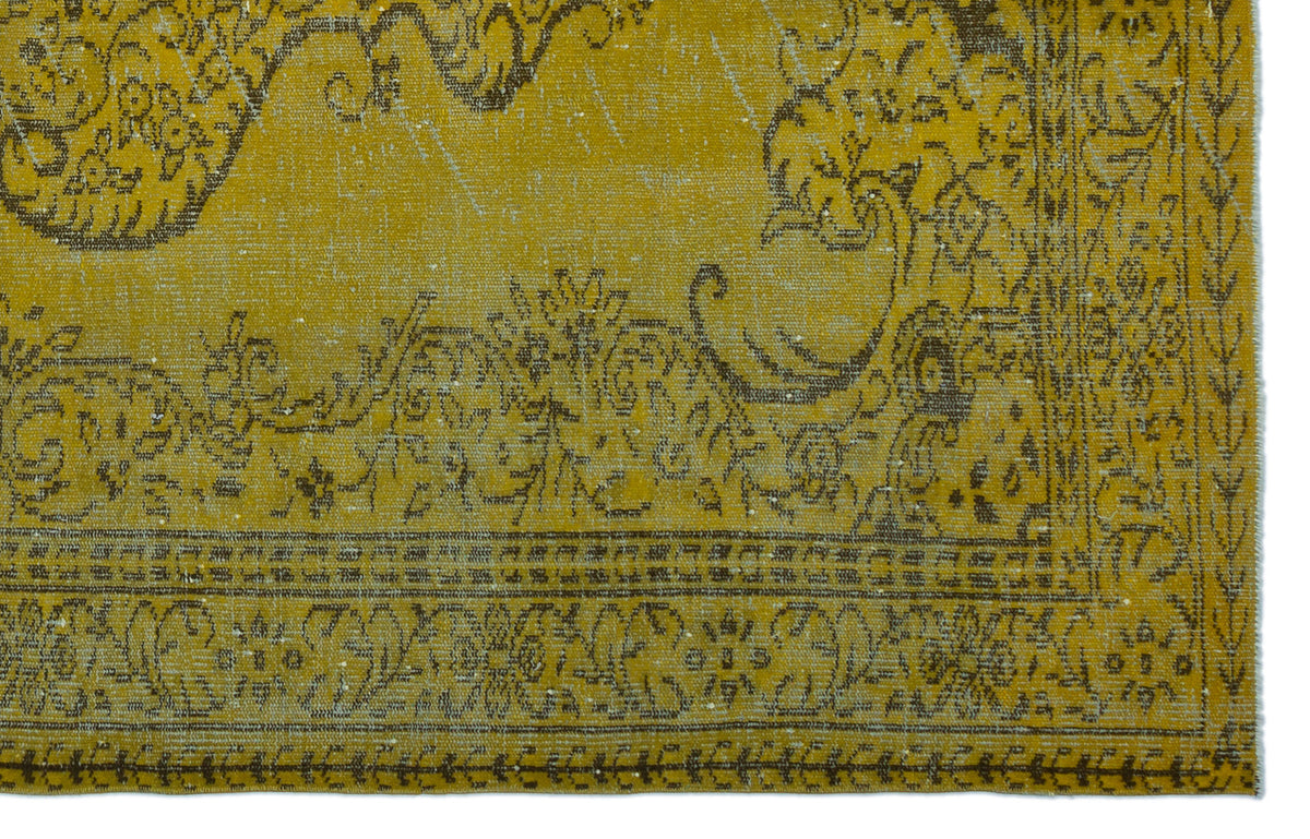 Mustard yellow rug with a distressed dark brown floral medallion pattern and a decorative border.