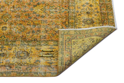 Load image 1 in gallery view. Distressed yellow and green vintage-style rug with a floral medallion pattern and a folded corner on a white background.