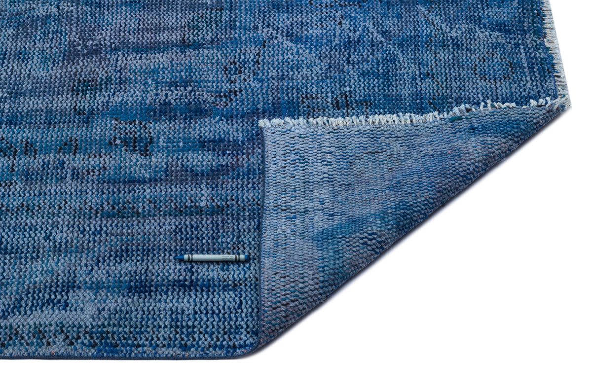 Blue distressed-texture rug with a folded corner and a blue crayon for scale on a white background.