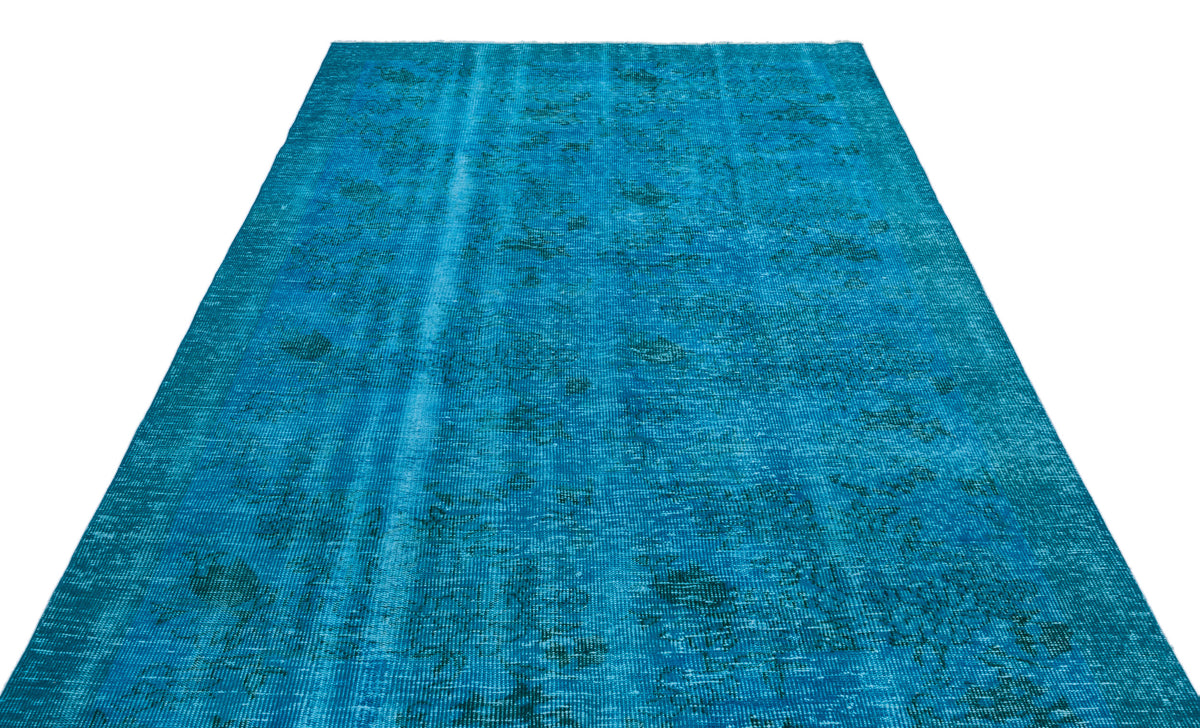 Bright blue distressed overdyed rug with a faint, traditional faded medallion pattern on a white background.