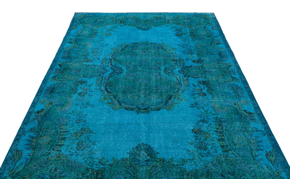 Bright turquoise and dark teal distressed rug with a traditional central medallion and ornate floral border.