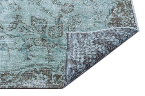 Load image 1 in gallery view. Distressed sage green and brown floral medallion rug with a corner folded over to show the woven backing.