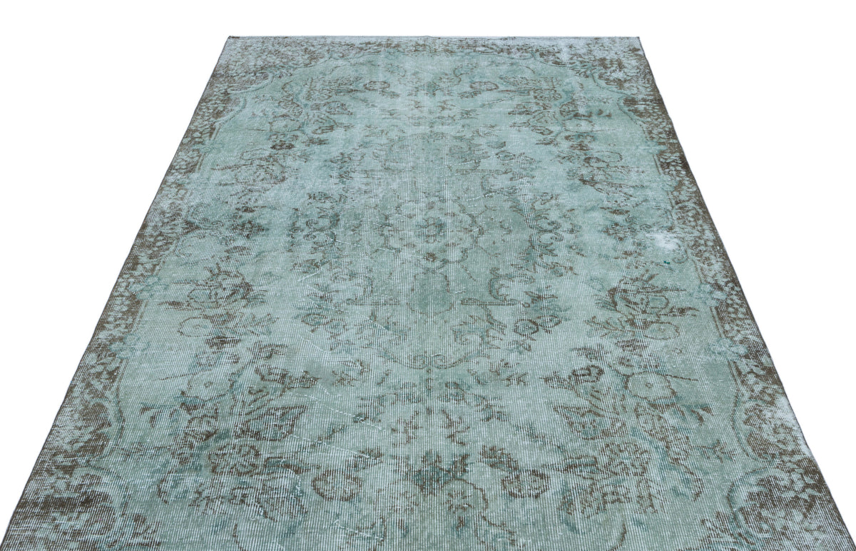 Distressed light blue and grey vintage-style rug with a faded floral medallion pattern on a white background.