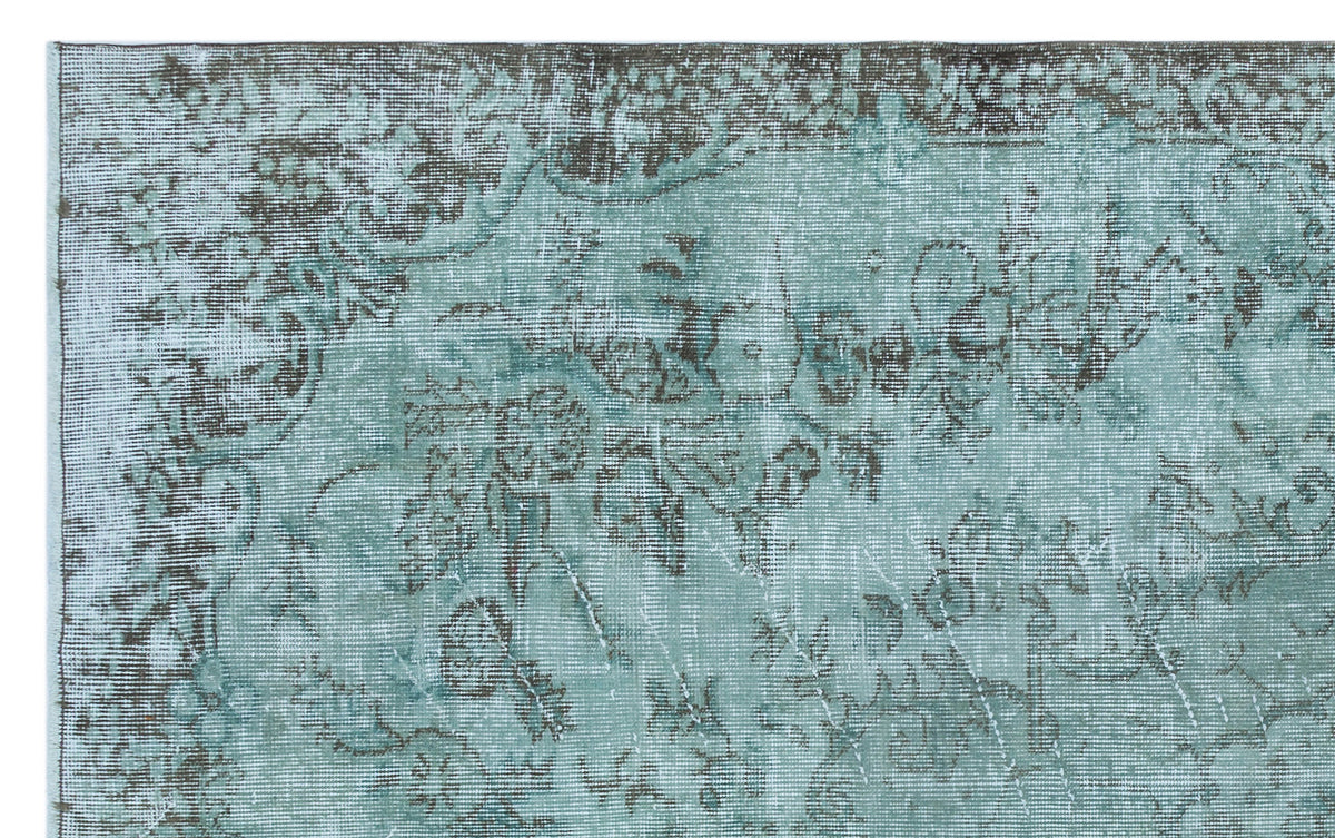 Distressed teal and charcoal rug with a faded traditional floral medallion pattern.