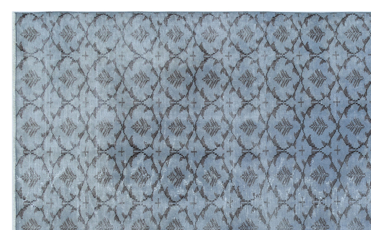 Slate blue rug with a dark grey repeating lattice and floral medallion pattern.