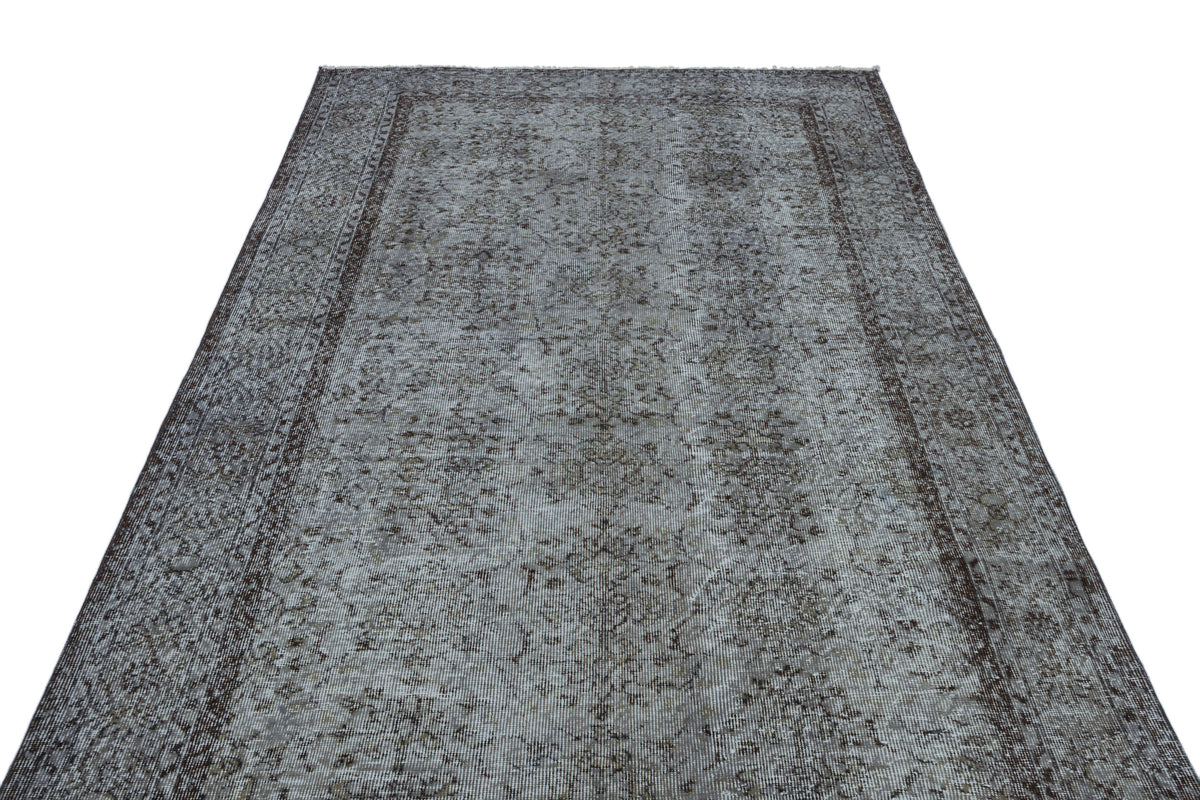 Grey and brown distressed vintage-style rug with a faded floral medallion pattern and a dark border.