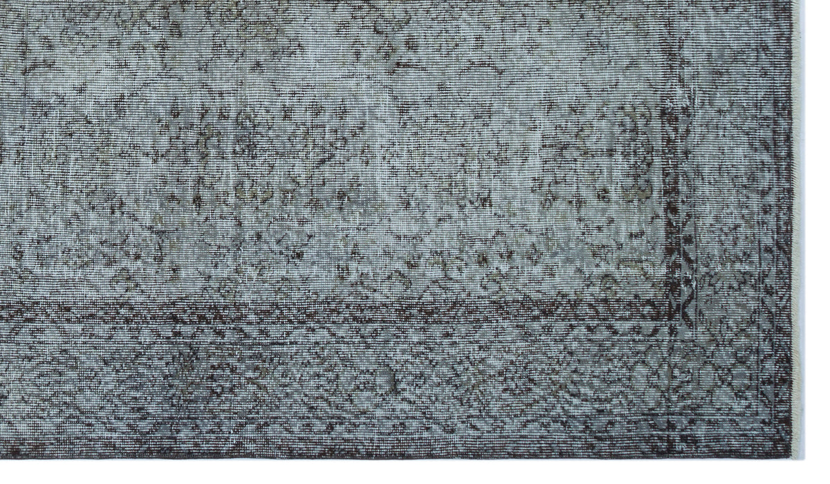 Grey and charcoal distressed rug with a faded traditional floral medallion pattern and a dark geometric border.
