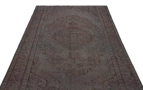 Load image 1 in gallery view. Dark brown and charcoal vintage-style rug with a faded central medallion and intricate border pattern.