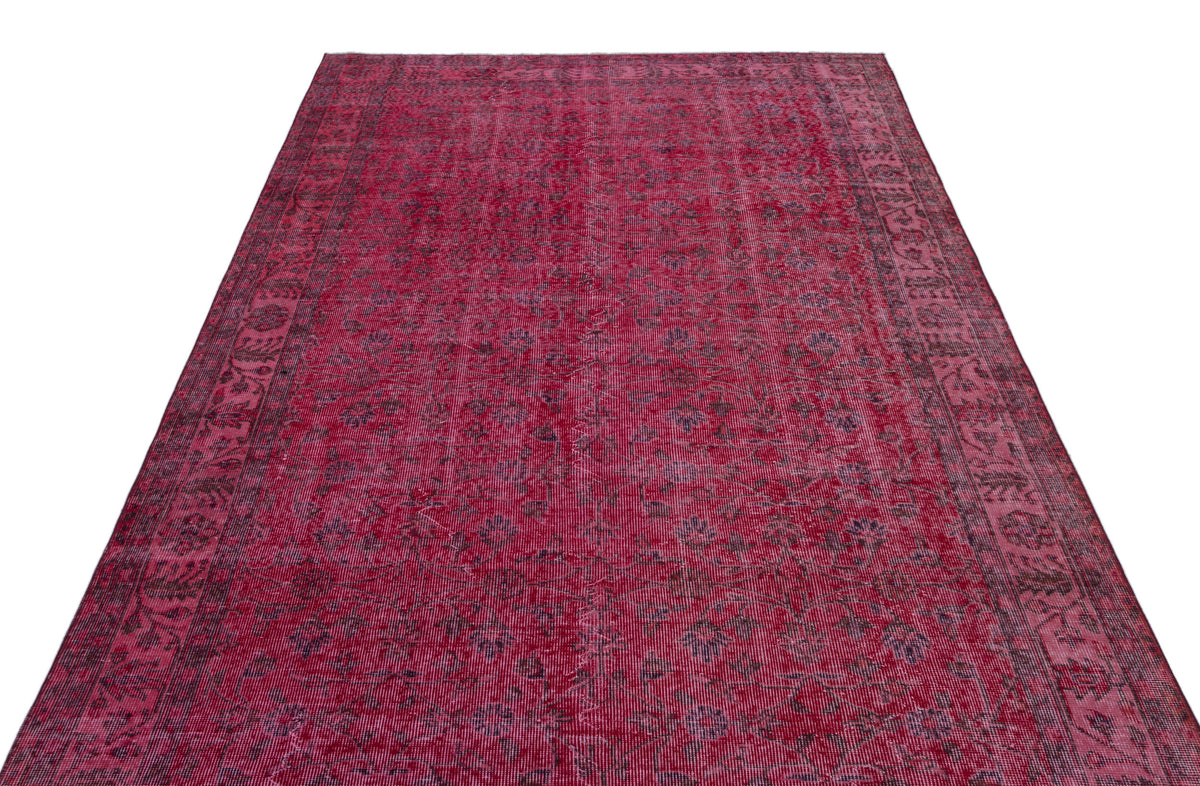 Deep red vintage-style rug with a faded floral medallion pattern and a dark decorative border.