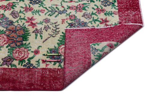 Load image 1 in gallery view. Cream rug with a red border and multi-colored floral pattern, shown with a corner folded over and two crayons.