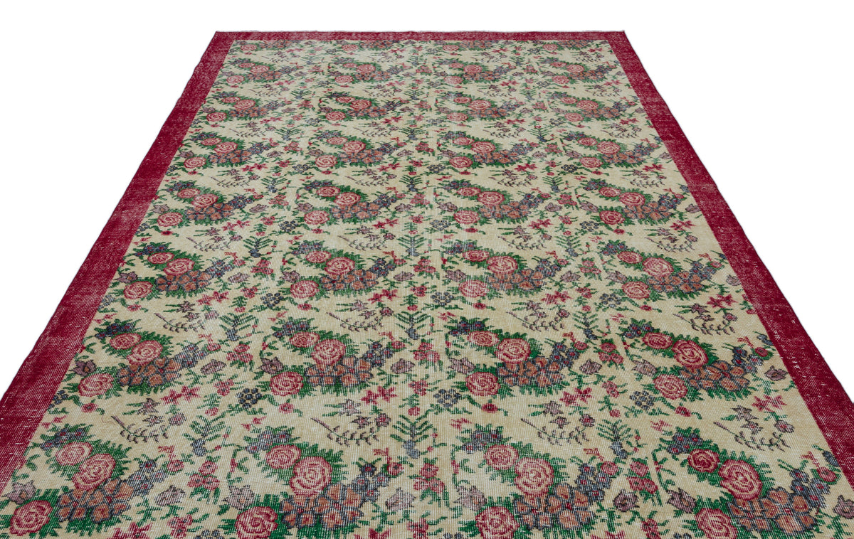 Cream rug with a red border and a repeating floral pattern in shades of red, green, and blue.