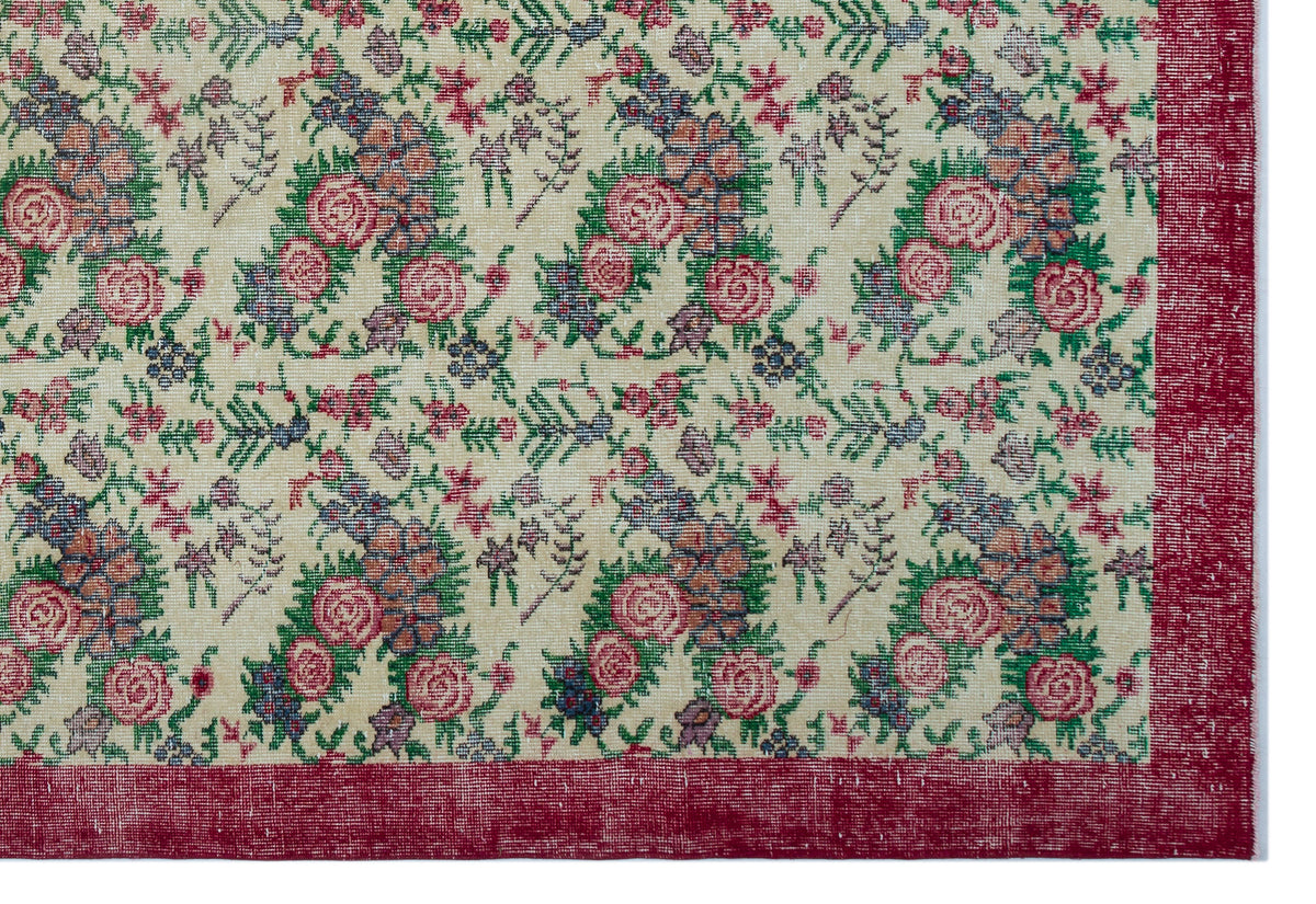 Cream rug with a floral pattern in pink, green, and blue, featuring a wide, distressed red border.
