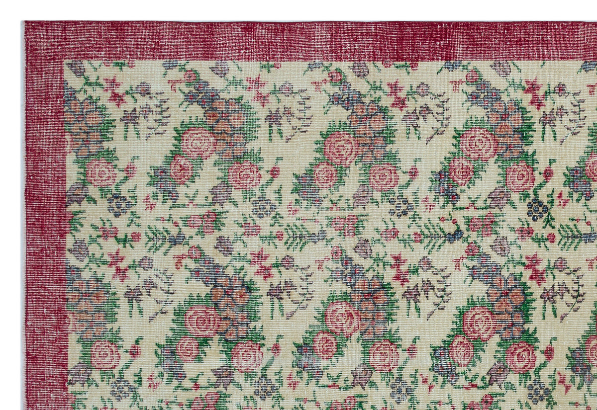 Cream rug with a distressed floral pattern in red, green, and blue, featuring a wide red border.