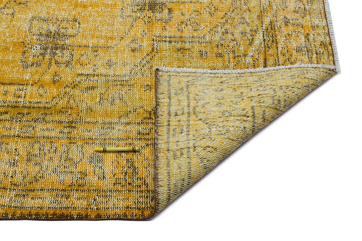 Mustard yellow and brown distressed traditional rug with a folded corner, isolated on a white background.